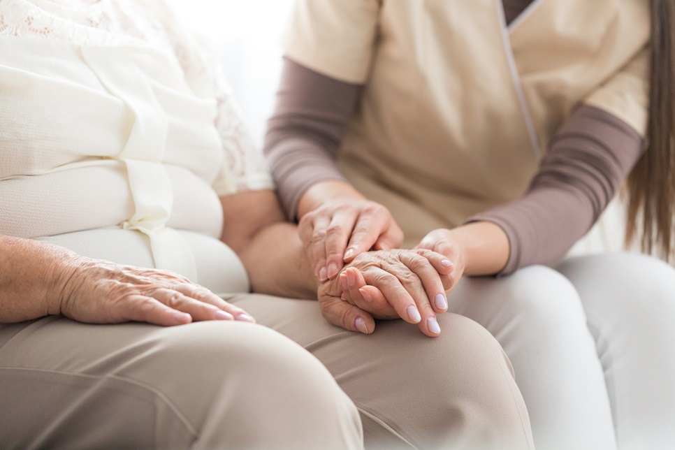 Kobieta trzymająca za rękę starszą osobę cierpiącą na osteoporozę
